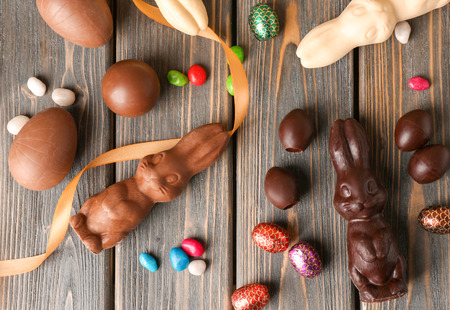 Beautiful Easter composition with chocolate bunnies, eggs and candies on wooden backgroundの写真素材