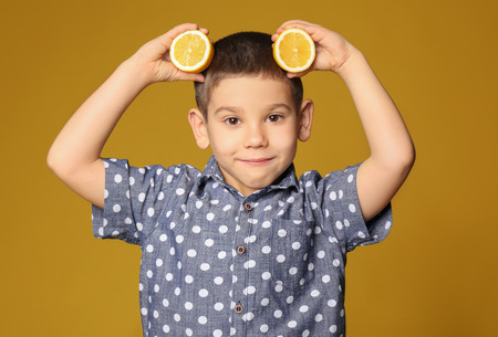 Funny little boy with citrus fruit on color backgroundの写真素材