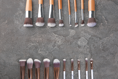 Flat lay composition with professional cosmetic brushes on grey background