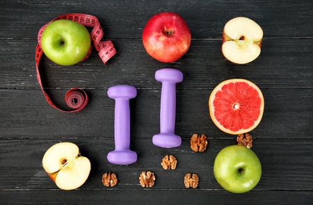 Fresh fruits and dumbbells on wooden background. Diet foodの写真素材