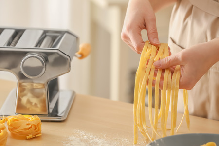 Woman preparing pasta at tableの写真素材