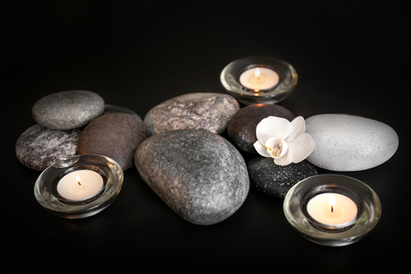 Beautiful composition with spa stones and burning candles on black backgroundの写真素材