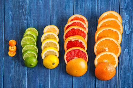 Slices of fresh citrus fruits on wooden table, flat lay