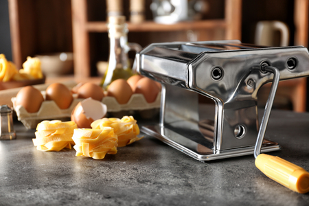 Metal pasta maker and products on kitchen tableの写真素材