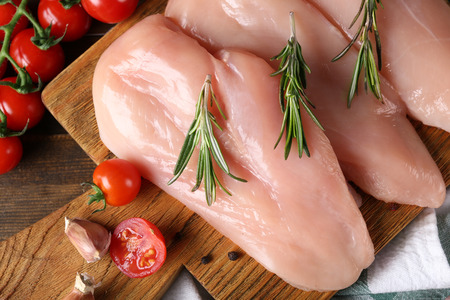 Raw chicken fillet on wooden board, closeupの写真素材