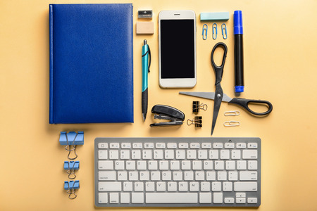 Workplace with stationery, keyboard and phone on table. Top view