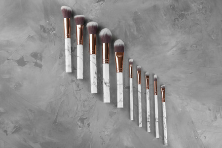 Flat lay composition with professional cosmetic brushes on grey background
