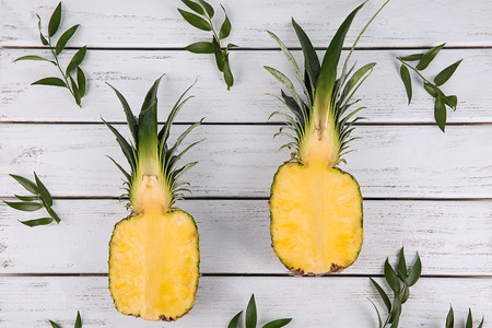 Composition with halves of ripe pineapple on wooden background