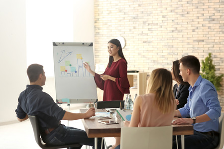 Young woman giving presentation during business meeting in officeの写真素材