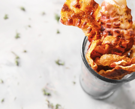 Fried bacon rashers in glass on tableの写真素材