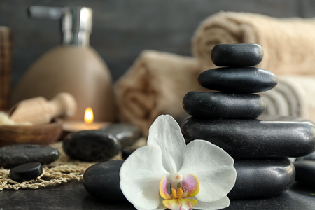 Beautiful spa composition with stones and orchid flower on tableの写真素材