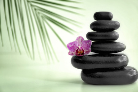Stack of spa stones and beautiful orchid flower on light backgroundの写真素材