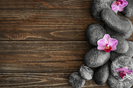Spa stones and beautiful orchid flowers on wooden backgroundの写真素材
