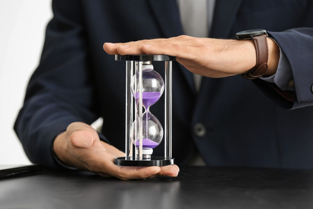 Man holding hourglass over table. Time management concept