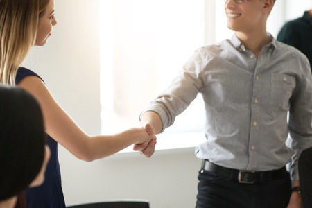 Young man and woman shaking hands at business meetingの写真素材
