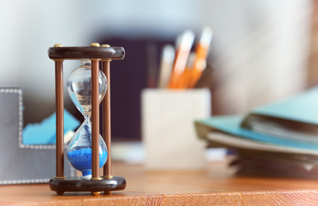 Hourglass on table against blurred background. Time management concept