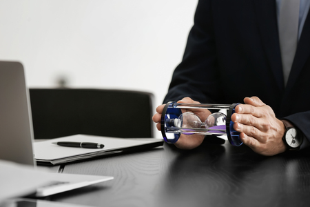 Man holding hourglass over table. Time management concept