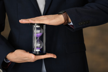 Man holding hourglass, closeup. Time management concept