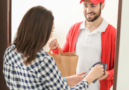 Young woman paying for food delivery with credit cardの写真素材
