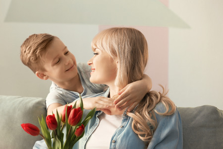 Portrait of cute little boy and his mother with tulip bouquet at homeの写真素材