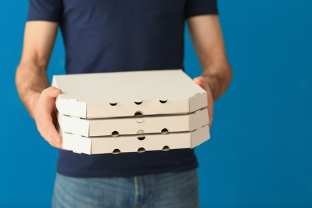 Delivery man with cardboard pizza boxes on color backgroundの写真素材