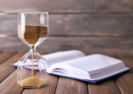Stylish hourglass and notebook on table. Time management concept