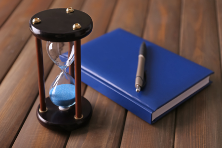 Stylish hourglass and notebook on table. Time management conceptの写真素材