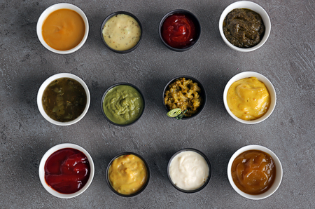 Different tasty sauces in bowls on grey tableの写真素材