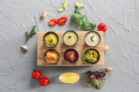 Different tasty sauces in bowls on grey background