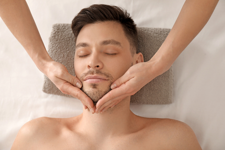 Handsome man having facial massage in spa salonの写真素材