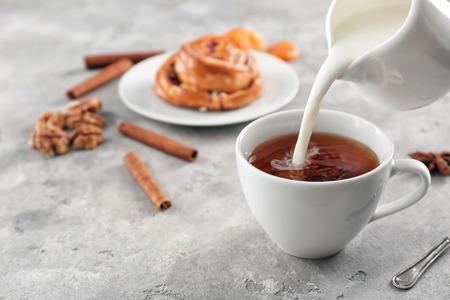 Adding milk to delicious tea on tableの写真素材