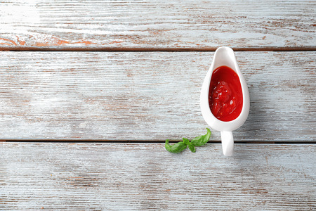 Gravy boat with delicious tomato sauce on wooden tableの写真素材