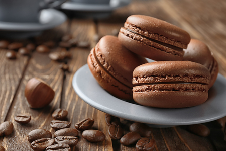 Plate with delicious chocolate macarons on wooden tableの写真素材