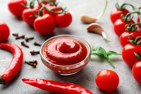 Composition with delicious tomato sauce and chili peppers on grey tableの写真素材