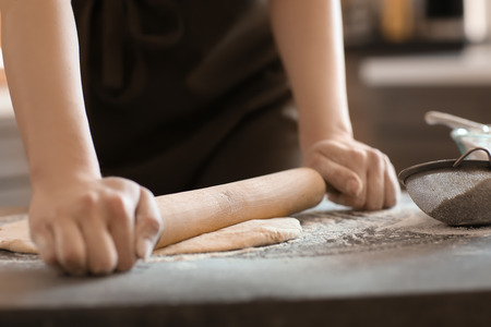 Baker rolling dough on kitchen table