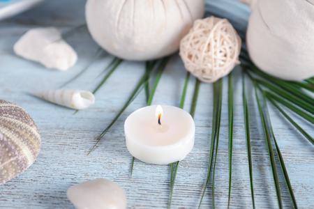 Beautiful spa composition with sea shells and burning candle on wooden backgroundの写真素材