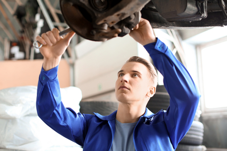 Male mechanic fixing car in service centerの写真素材