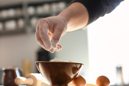Baker taking flour from bowl on kitchen table