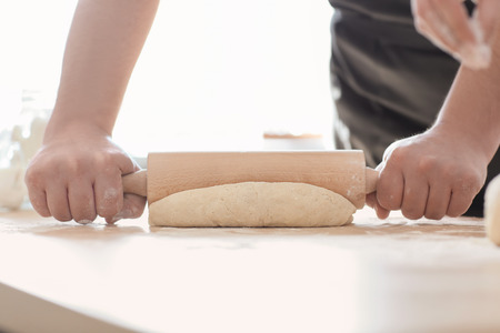 Baker rolling dough on kitchen table