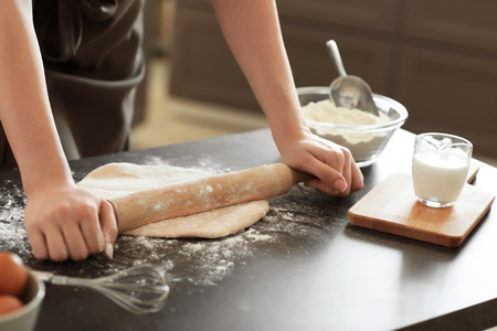 Baker rolling dough on kitchen table