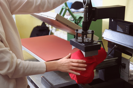 Young woman printing on cap at workshopの写真素材