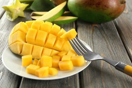 Fork and plate with fresh cut mango on table, closeupの写真素材