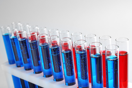 Test tubes with colorful liquids in holder on light backgroundの写真素材