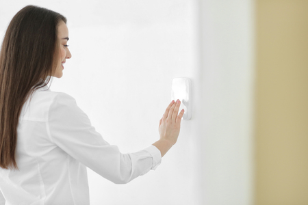 Young woman using security system indoors