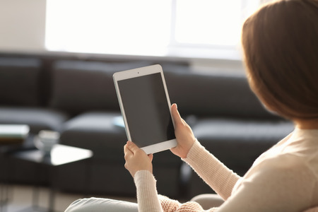 Young woman using tablet while resting at homeの写真素材