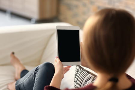 Young woman using tablet while resting on sofa at home