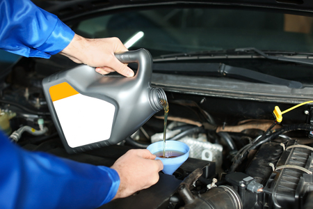 Male mechanic refilling car oil in service centerの写真素材