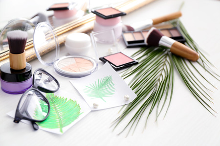 Set of cosmetic products and palm leaf on tableの写真素材