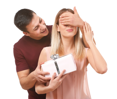 Young man giving present to his beloved girlfriend on white backgroundの写真素材