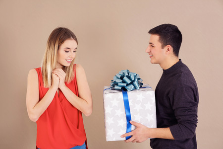 Young man giving present to his beloved girlfriend on color backgroundの写真素材